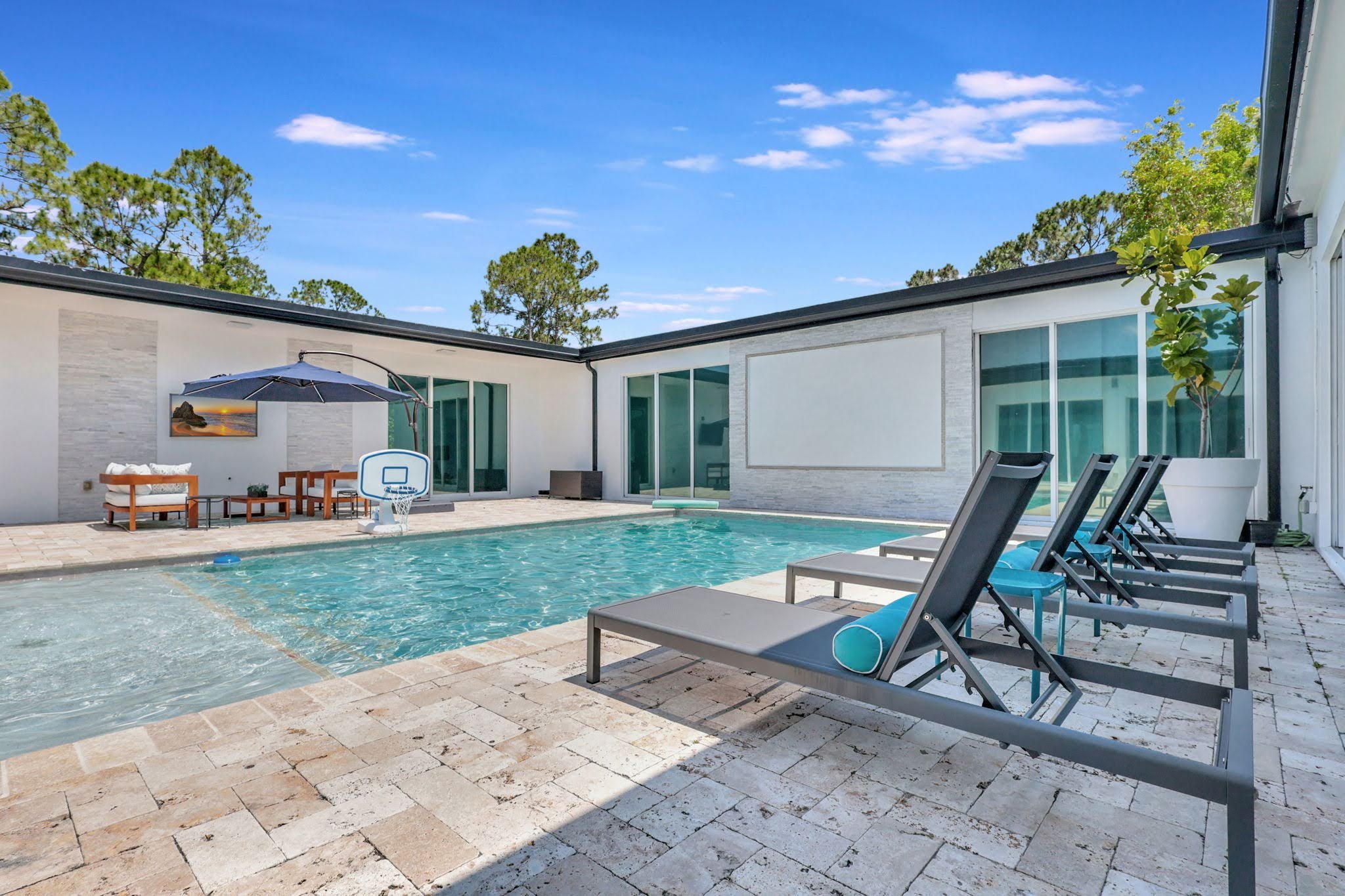 Private courtyard pool and stone patio with lounge chairs at Villa Verano in Loxahatchee